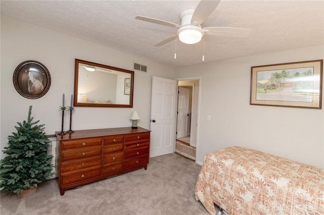 bedroom featuring ceiling fan, light carpet, and a textured ceiling