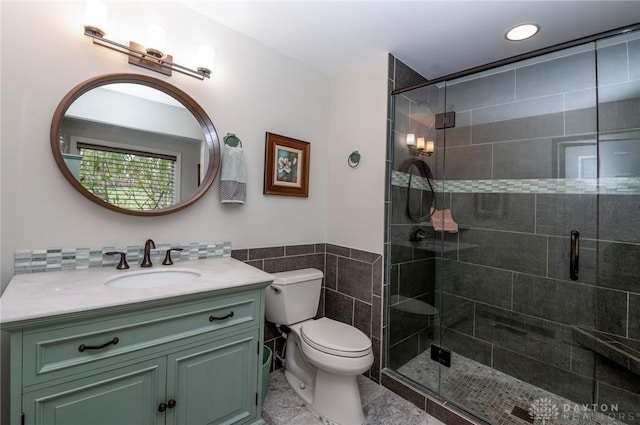 bathroom featuring vanity, a shower with door, tile walls, tile patterned flooring, and toilet