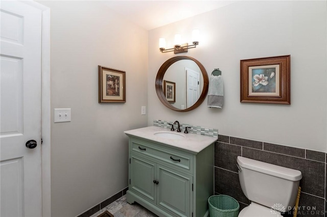 bathroom featuring vanity, toilet, and tile walls