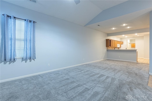 unfurnished living room with light colored carpet and vaulted ceiling