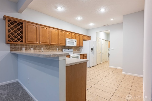 kitchen with tasteful backsplash, kitchen peninsula, a textured ceiling, white appliances, and light tile patterned floors