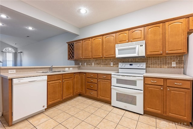 kitchen with white appliances, sink, vaulted ceiling, light tile patterned floors, and kitchen peninsula