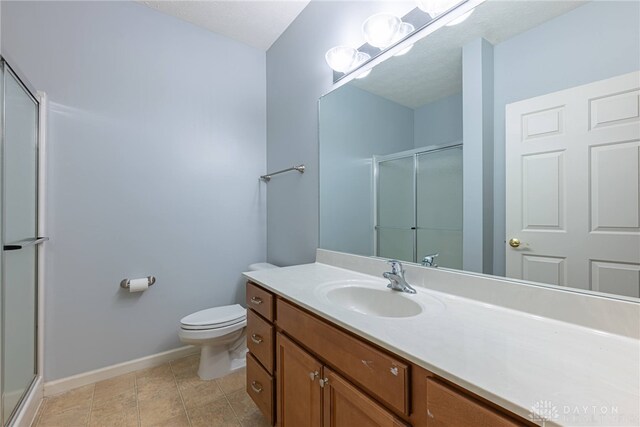 bathroom with tile patterned floors, vanity, toilet, and walk in shower