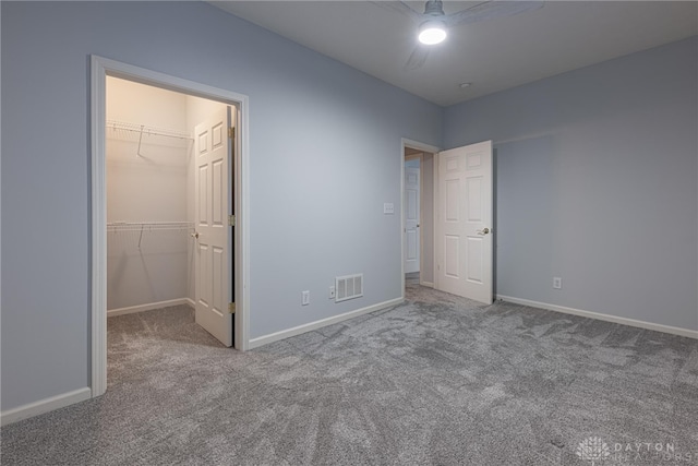 unfurnished bedroom featuring ceiling fan, a walk in closet, light carpet, and a closet