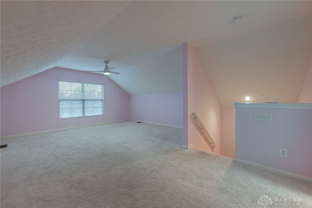 bonus room featuring a textured ceiling, light carpet, ceiling fan, and vaulted ceiling