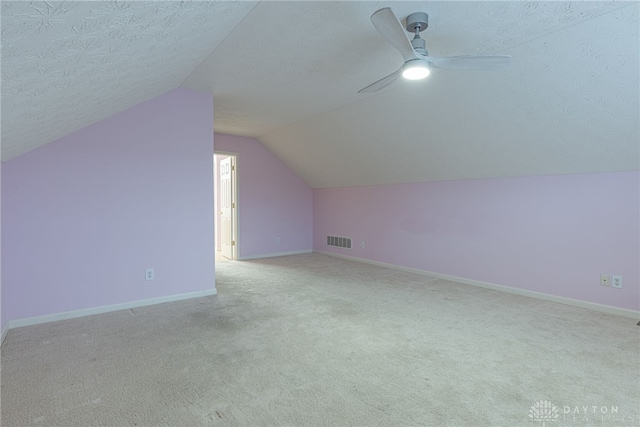 bonus room featuring a textured ceiling, light carpet, and vaulted ceiling