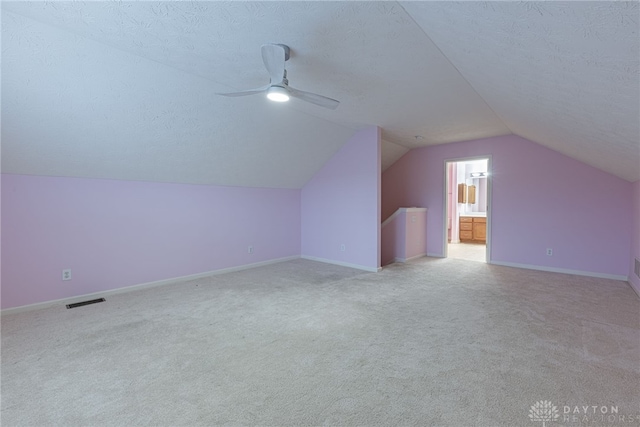 additional living space with light carpet, a textured ceiling, ceiling fan, and lofted ceiling