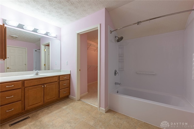 bathroom featuring vanity, a textured ceiling, and bathing tub / shower combination