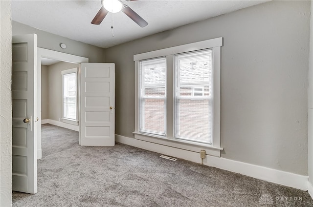 carpeted empty room featuring plenty of natural light and ceiling fan