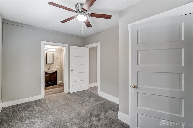 unfurnished bedroom with carpet floors, ensuite bathroom, ceiling fan, and sink