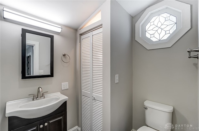 bathroom with vanity, toilet, and lofted ceiling