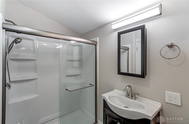 bathroom featuring vanity, vaulted ceiling, and walk in shower