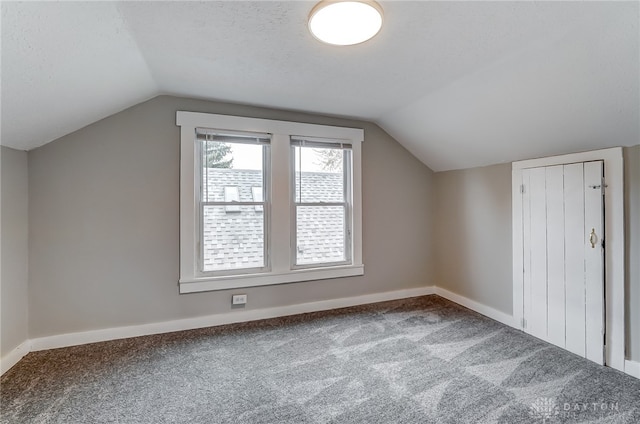 bonus room featuring carpet, lofted ceiling, and a textured ceiling