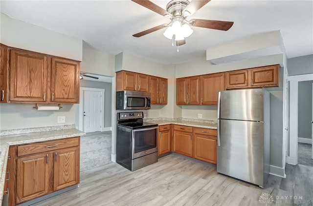 kitchen featuring ceiling fan, appliances with stainless steel finishes, and light hardwood / wood-style flooring