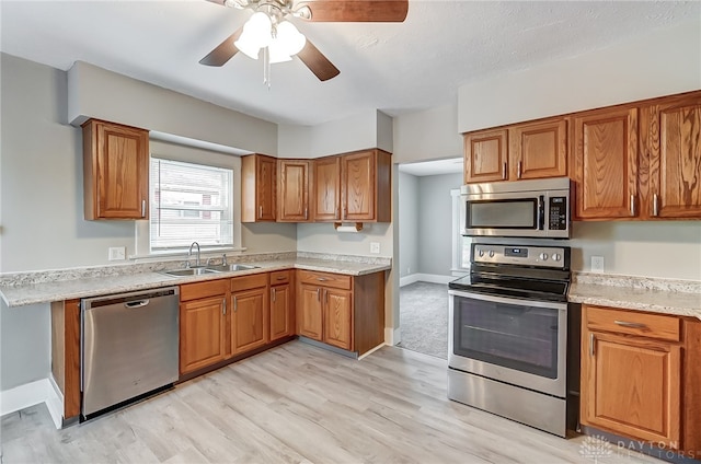 kitchen with stainless steel appliances, ceiling fan, light hardwood / wood-style floors, and sink