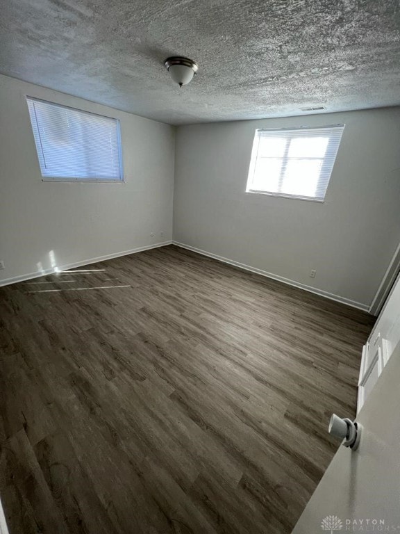 spare room featuring a textured ceiling and dark hardwood / wood-style floors