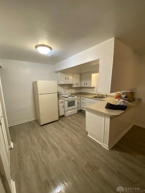 kitchen featuring kitchen peninsula, white appliances, sink, hardwood / wood-style floors, and white cabinetry