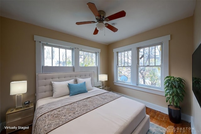 bedroom with parquet flooring, multiple windows, and ceiling fan