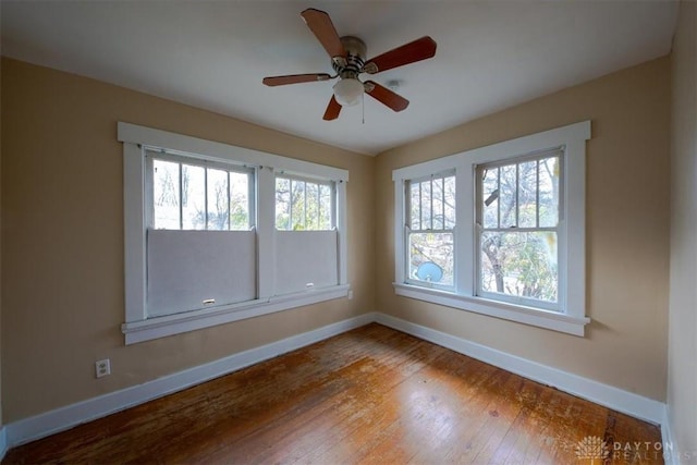 empty room with ceiling fan, plenty of natural light, and hardwood / wood-style flooring