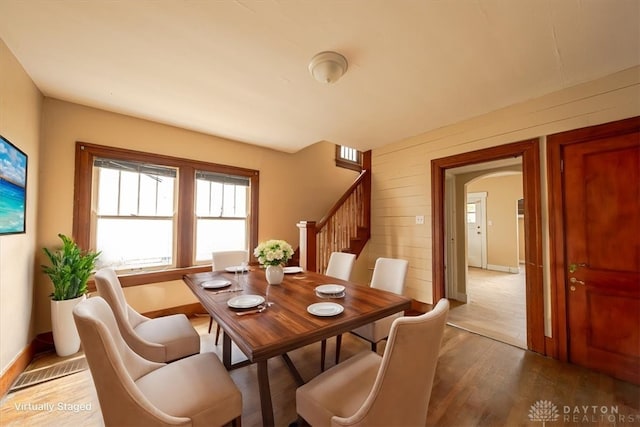 dining space featuring hardwood / wood-style floors and wooden walls