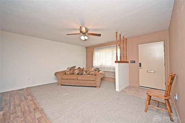 living room with a textured ceiling, light hardwood / wood-style flooring, and ceiling fan