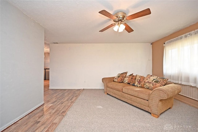 living room featuring ceiling fan, wood-type flooring, and a textured ceiling