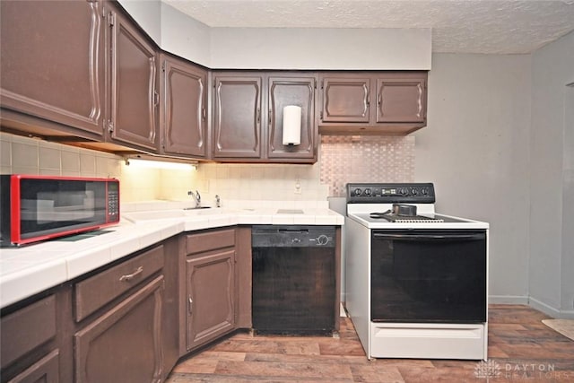 kitchen featuring sink, tile counters, backsplash, light hardwood / wood-style floors, and black appliances