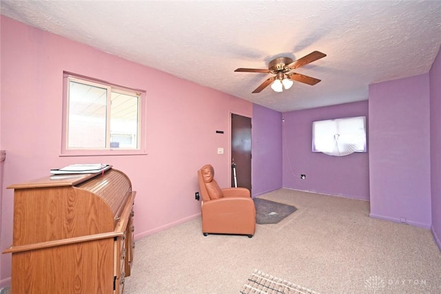 living area featuring ceiling fan, a healthy amount of sunlight, light colored carpet, and a textured ceiling