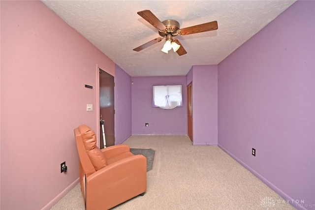 living area with light carpet, a textured ceiling, and ceiling fan