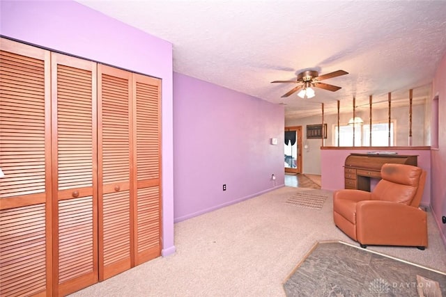 living area featuring carpet flooring, ceiling fan, and a textured ceiling