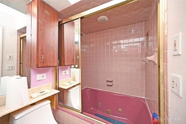 bathroom with toilet and shower / bath combination with glass door