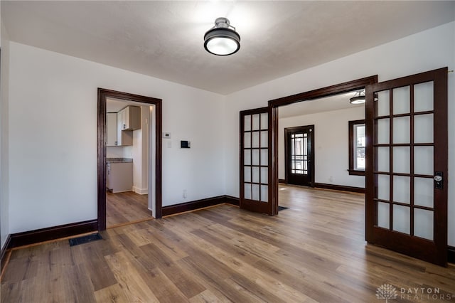 empty room with french doors and wood-type flooring