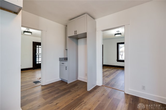 kitchen featuring light stone countertops, white cabinetry, and dark wood-type flooring