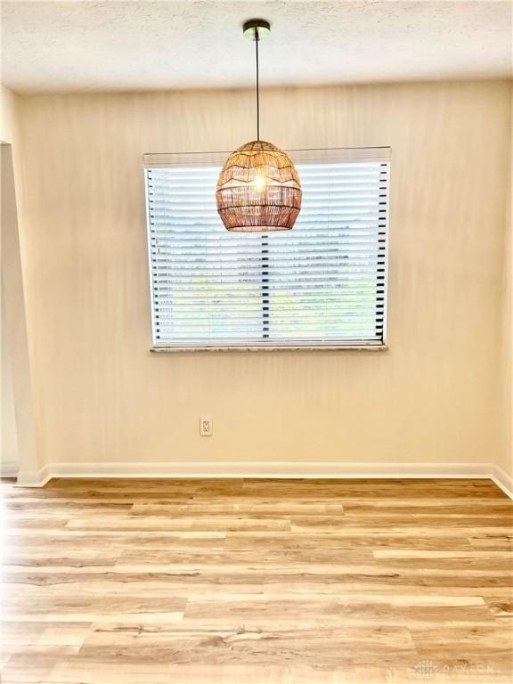 unfurnished dining area with hardwood / wood-style floors and a textured ceiling