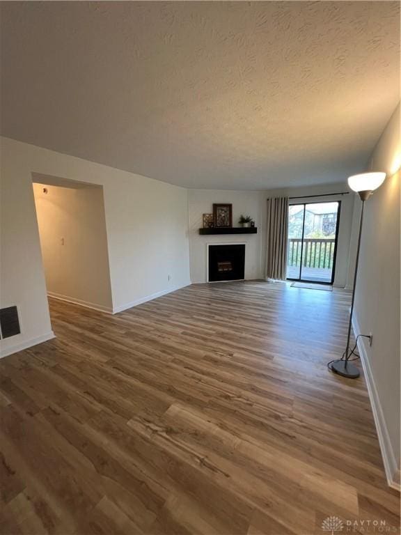 unfurnished living room with wood-type flooring and a textured ceiling