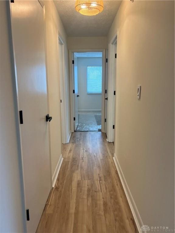 hall featuring light hardwood / wood-style floors and a textured ceiling