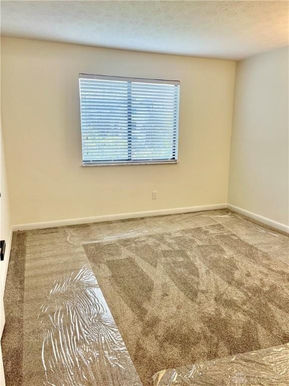 spare room featuring a textured ceiling and carpet floors