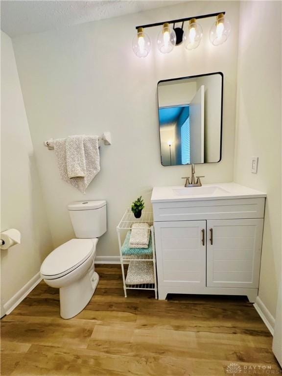 bathroom with hardwood / wood-style floors, vanity, and toilet