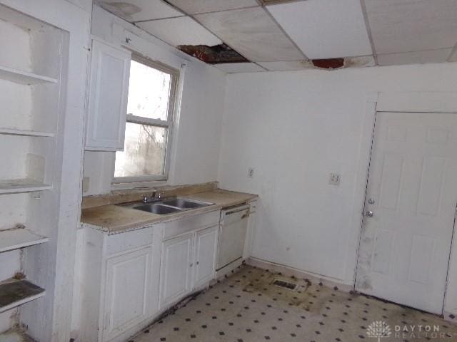 kitchen featuring light floors, white dishwasher, white cabinetry, light countertops, and open shelves