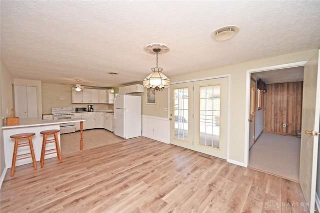 kitchen featuring a peninsula, white appliances, light wood-style floors, light countertops, and pendant lighting