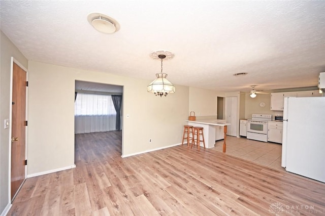 interior space featuring a textured ceiling, light wood-type flooring, and baseboards