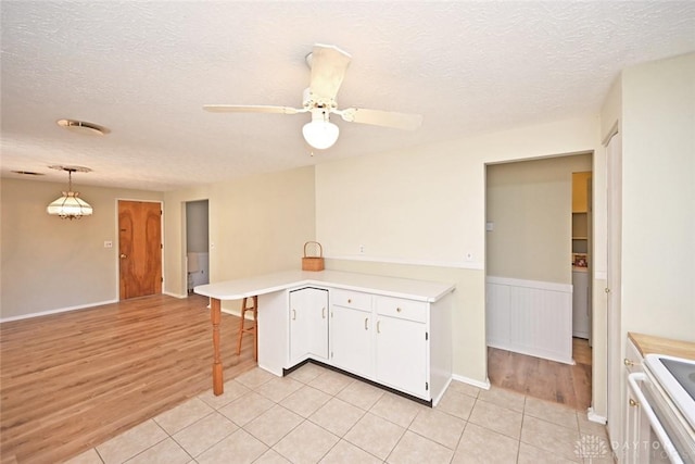 kitchen with light wood-style flooring, white cabinets, light countertops, and a peninsula