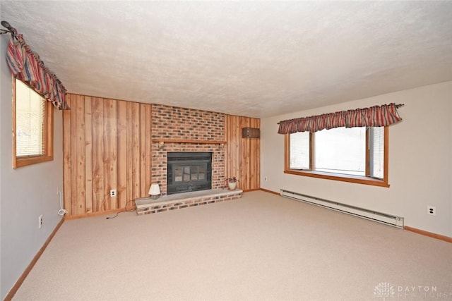 unfurnished living room with wood walls, a fireplace, a baseboard heating unit, and carpet flooring