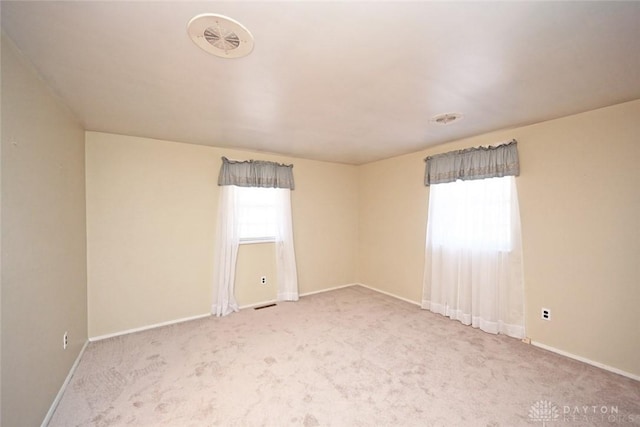 carpeted spare room featuring a wealth of natural light and baseboards