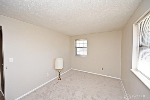 carpeted empty room with a textured ceiling and baseboards