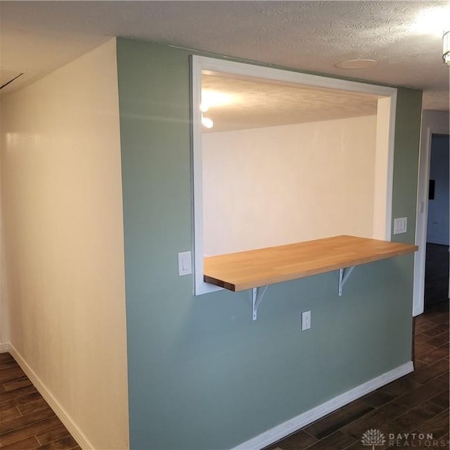 kitchen featuring a textured ceiling, a kitchen bar, and dark wood-type flooring