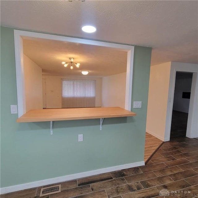1246 Angiers Dr, Dayton, OH 45417 - kitchen featuring wood finish floors, visible vents, a peninsula, and a kitchen bar