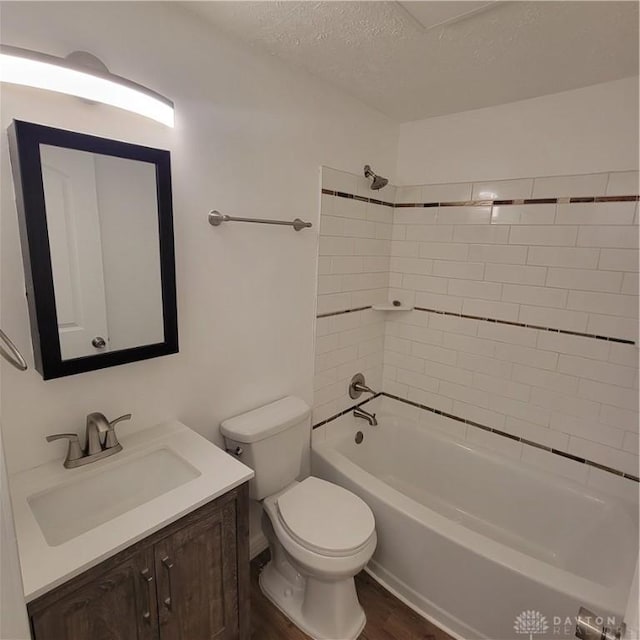 full bathroom featuring vanity, a textured ceiling, wood-type flooring, toilet, and tiled shower / bath