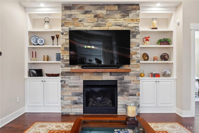 living room featuring a fireplace, built in shelves, and dark wood-type flooring