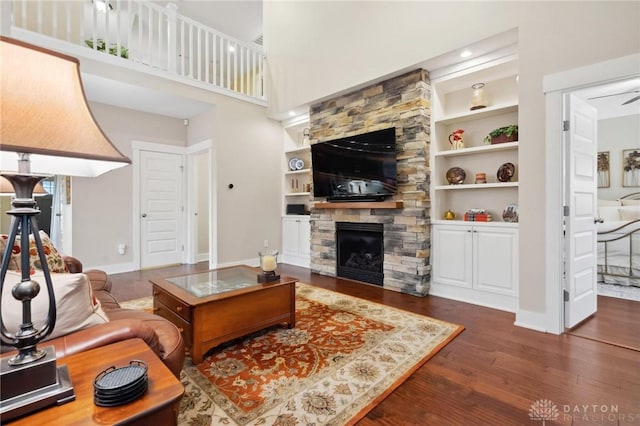 living room featuring a fireplace, ceiling fan, built in features, and dark hardwood / wood-style floors